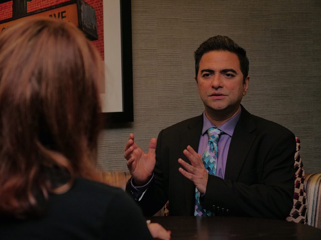 Man in suit conversing with woman indoors.