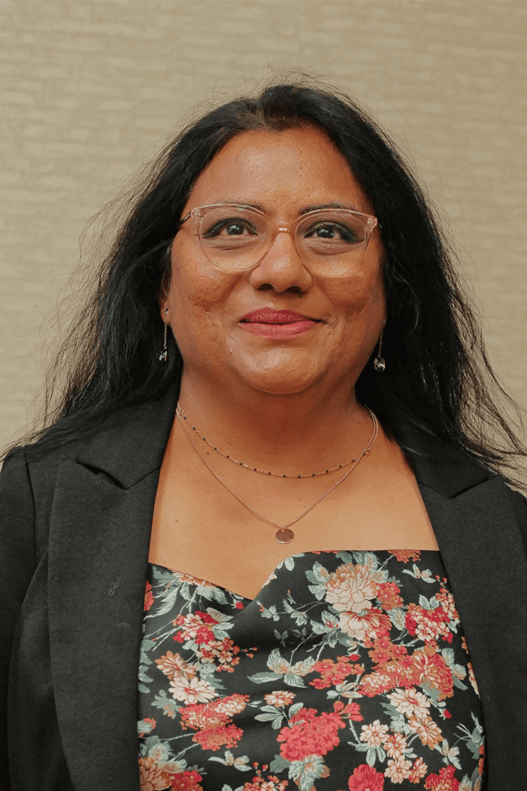 Smiling woman with glasses and floral top.