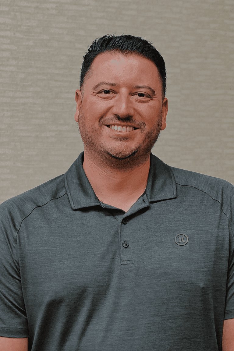 Smiling man in gray polo shirt indoors.
