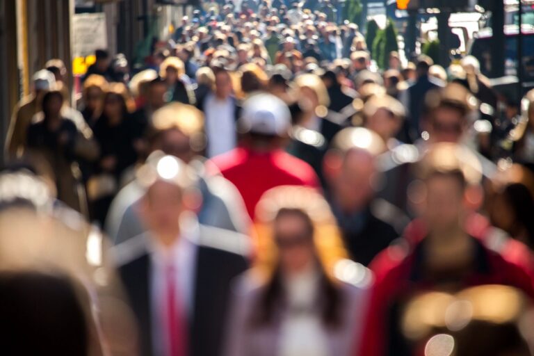 Crowded street scene with blurred people walking.